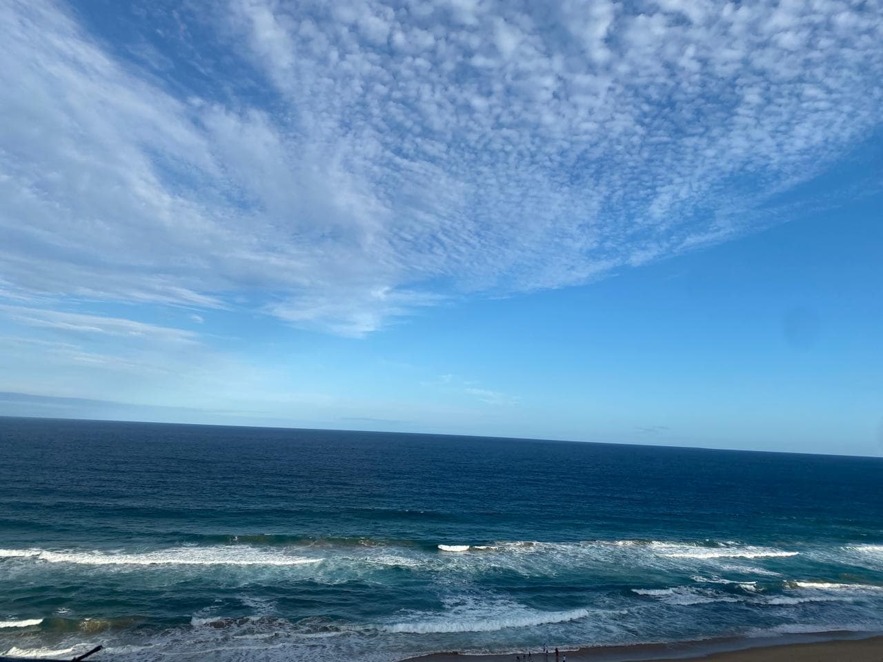 Expansive view of the ocean meeting a cloudy blue sky